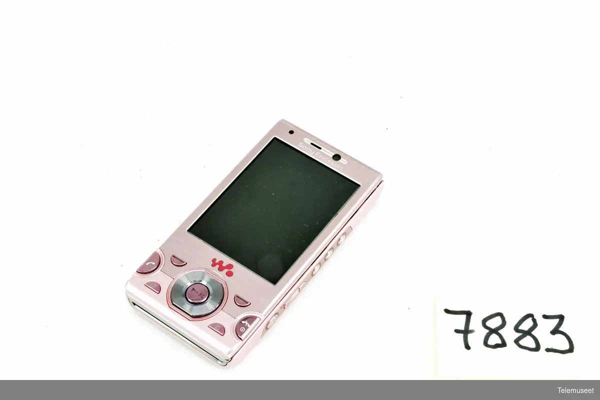 Rosa mobiltelefon med tilhørende utstyr som: lader, minnepinne, datakabel, informasjons brosjyrer og fire gummi ørebeskyttere til hodetelefon. Batteri, Netcom simkort og 8GB minnebrikke medfølger. Mangler hodetelefoner, bruksanvisning og mulig et nakkebånd.