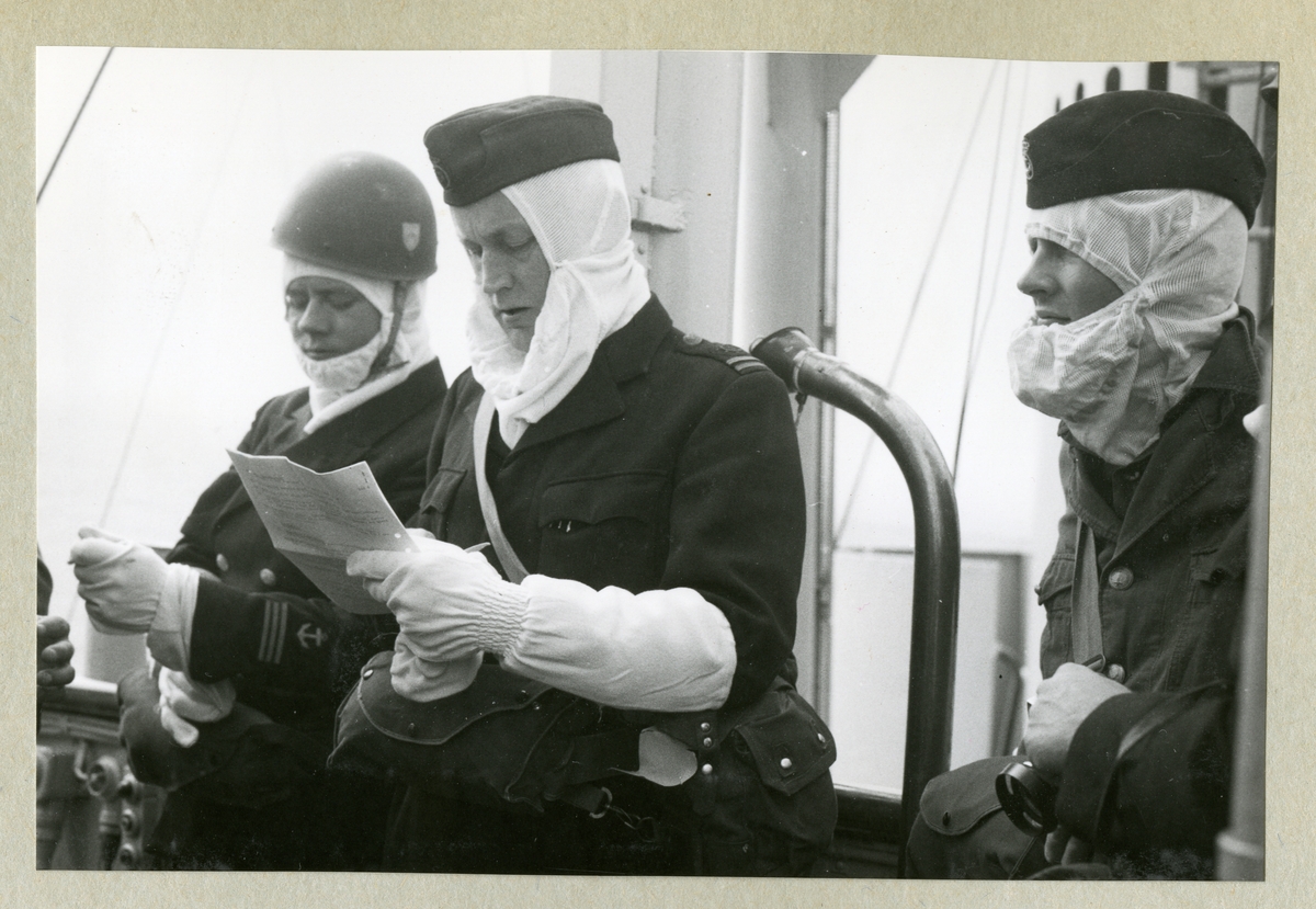 Bilden föreställer tre uniformsklädda besättningsmedlemmar med vita huvor och handskar ombord på minfartyget Älvsnabben under långresan 1966-1967.