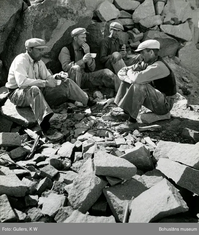 Fyra stenhuggare sitter i ett stenbrott och dricker kaffe