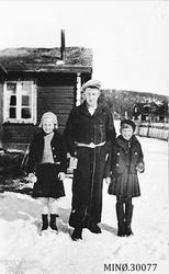 Mann og to jenter foran lite bolighus - Knutsenhuset. 
Fv: 