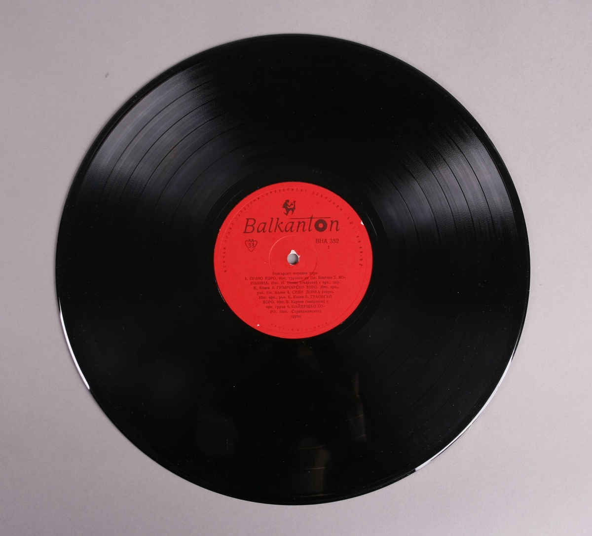 Grammofonplate i svart vinyl med plateomslag av papir. Platen ligger i en plastlomme. Det er påskrift på baksiden av plateomslaget (se bilde).