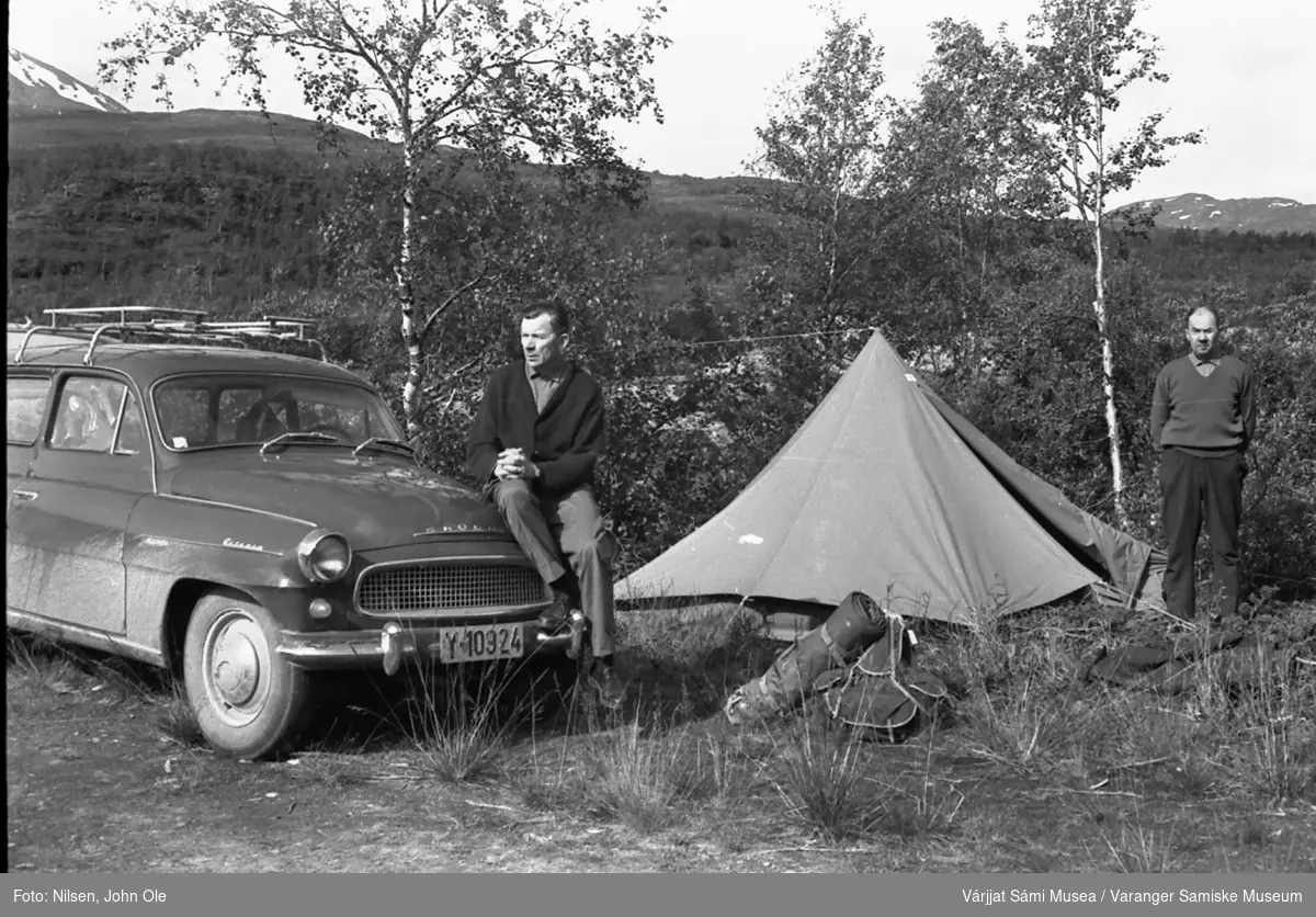 John Ole Nilsen og Henrik Ravna på biltur. De har parkert og satt opp telt ved en sidevei. Bilen en Skoda Oktavia stasjonsvogn med eieren John Ole Nilsen sittende på skjermen. Henrik Ravna står ved teltet. Det ser ut som om det er et vann i bakgrunnen. Skibotndalen 16. juli 1967