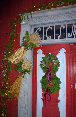 Julenek med rød sløyfe og kranser av grønt bar henger på en gammel dør. (Foto/Photo)