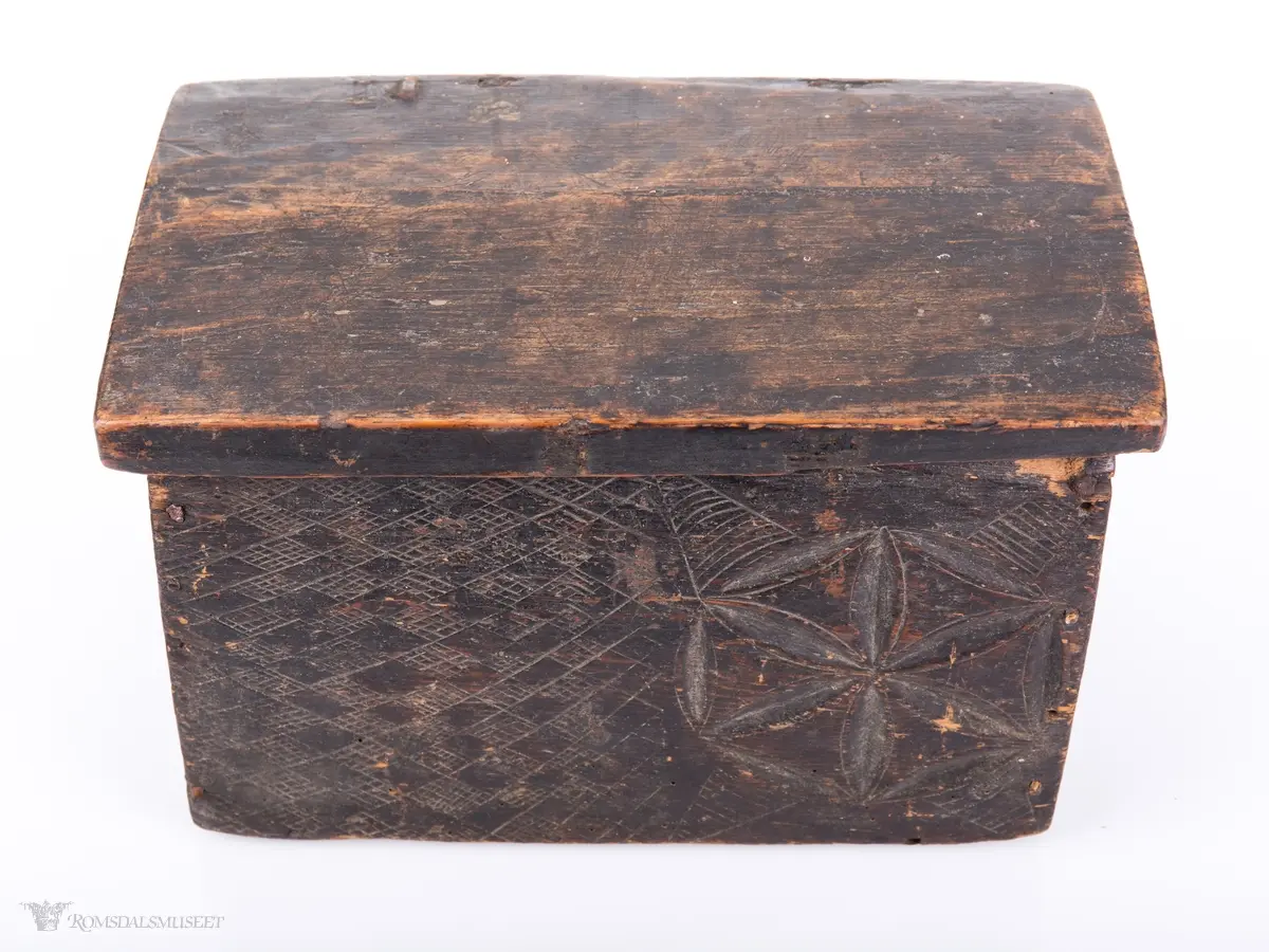 Seksbladsroser i karveskurd. 2 bak, en i front og en på hver korside. Rissede dekorfelt omkranser motivene.