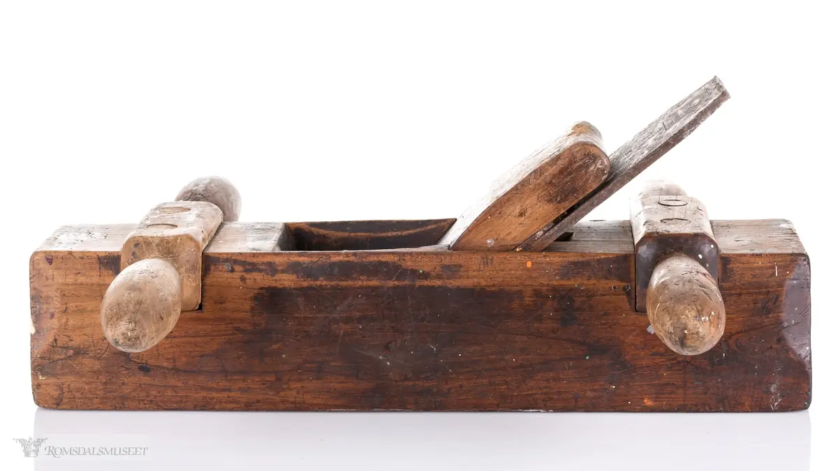 Oksehøvel i tre med rektangulær høvelstokk. Sponhus på toppen med høveljern med klaff og kile. Knekt av tre slått inn i bakkant.