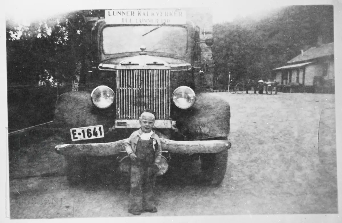 Liten gutt står foran en lastebil.