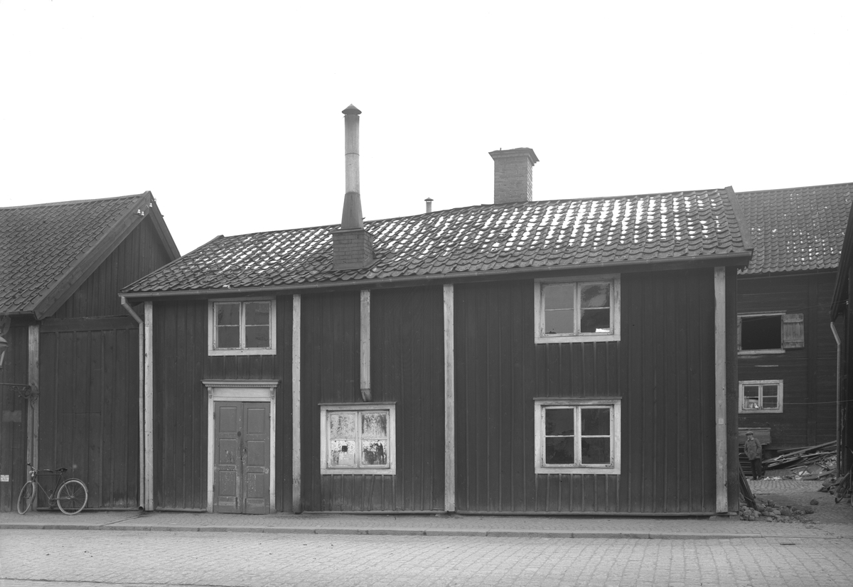 Tanneforsgatan 2 i Linköping. Året är 1926. Byggnaden är en i en länga av fyra hus som bildar front på Trädgårdstorgets västra sida. Inom kort skall husen rivas och ge plats för affärspalatset Delfinen.