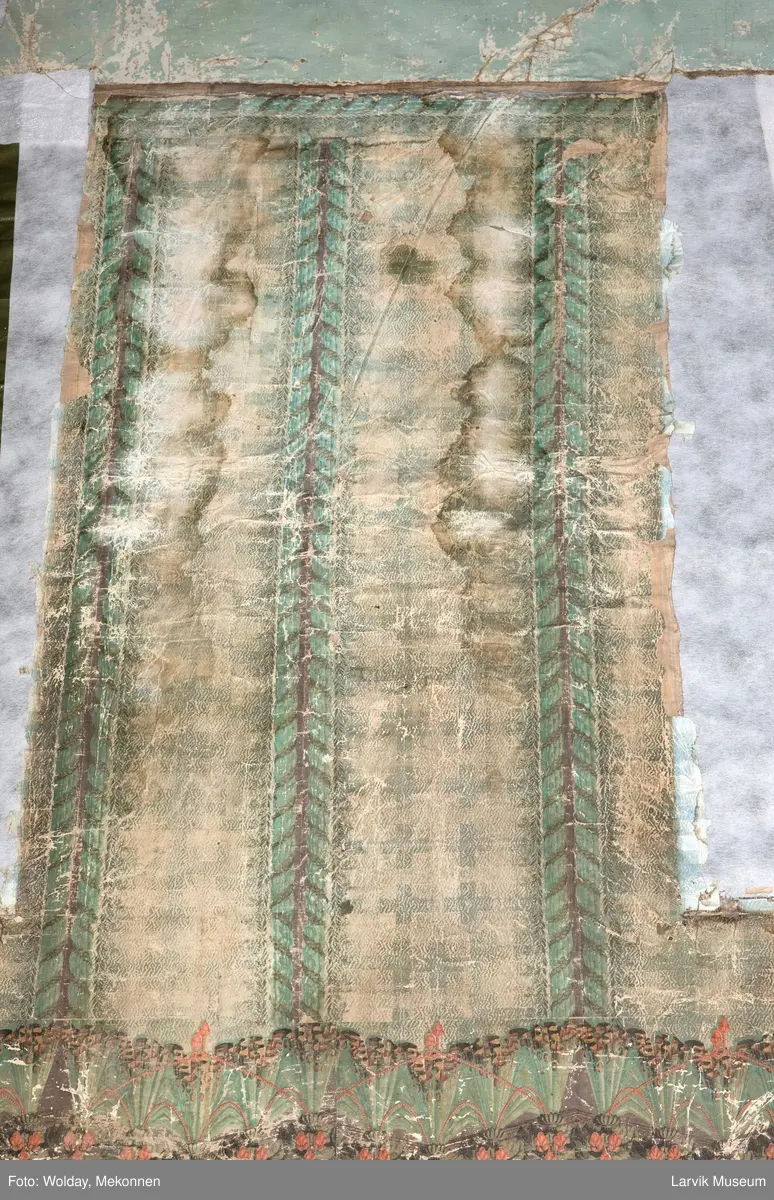 |Tapeten er påmalt tapetborder og brystning. Fra Hovland gård i Larvik.
Den øverste, brede borden: Gerlander/draperi med blomsterranker.
Den nederste, smalere borden: Tekstilbord med blomster. Øver døren til høyre: Stillebenmotiv med blomster og frukt.