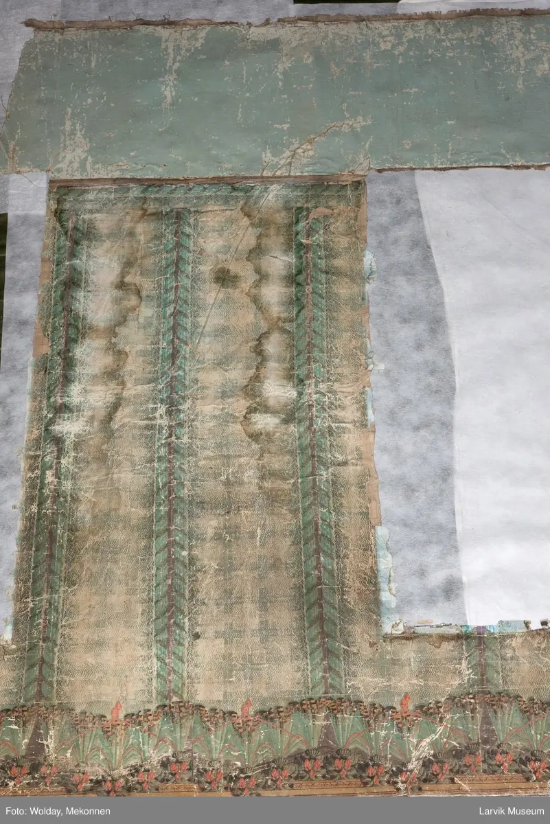 |Tapeten er påmalt tapetborder og brystning. Fra Hovland gård i Larvik.
Den øverste, brede borden: Gerlander/draperi med blomsterranker.
Den nederste, smalere borden: Tekstilbord med blomster. Øver døren til høyre: Stillebenmotiv med blomster og frukt.