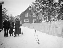 Mann, lien jente og kvinne i snøen med en mann i bakgrunn ve