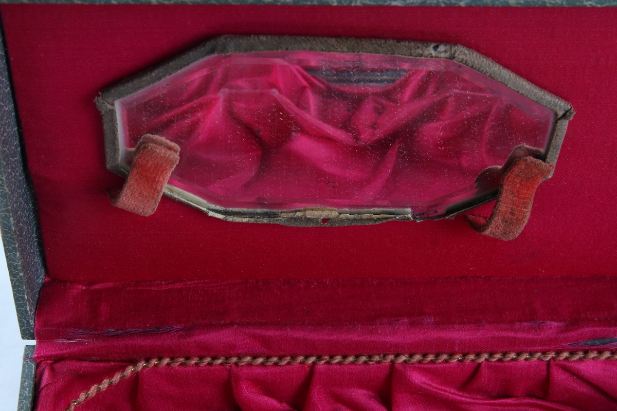 Smykkeskrin med hengsler og lås. Innsiden er foret med rødt silketøy. Et speil er festet på innsiden av lokket.