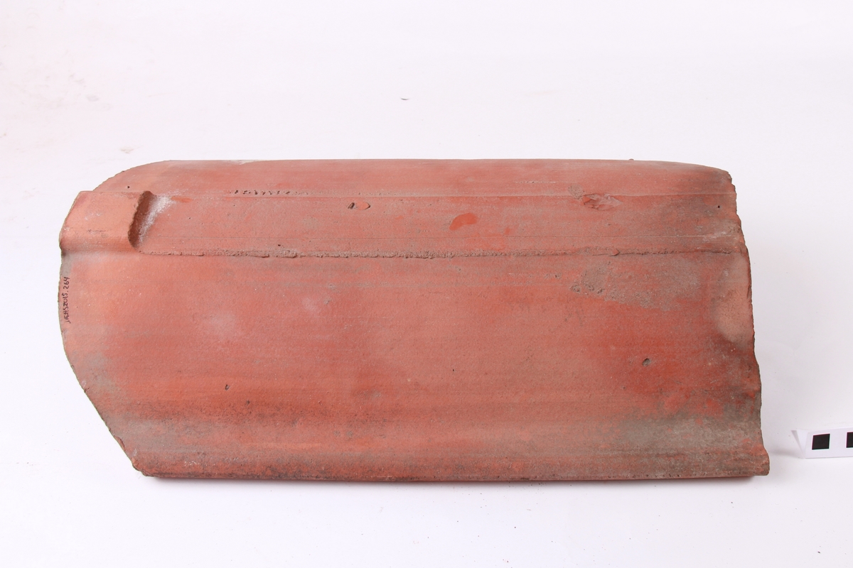 Krum takstein, maskinstrålte. Avskjering for panneknappen på baksida. Dette er den mest vanlege type takstein.