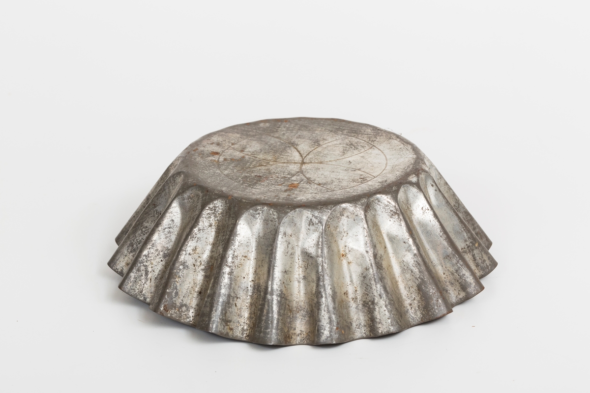 Kakeform for terte, også kalt terteform. Blomstdekor på bunnen av formen. Noe rust på formen.