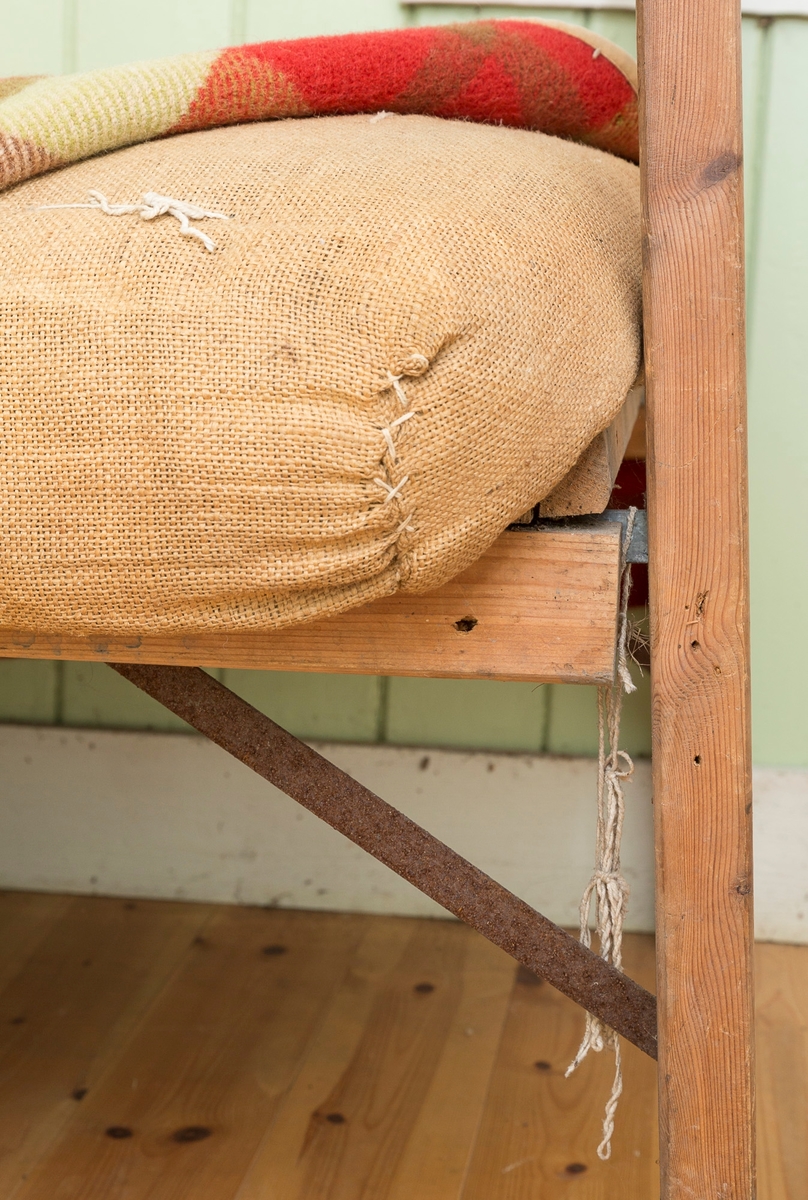 Sengeramme med sangegavler bestående av staver. Ubehandlet tre. Avstivere i metall. Nettingbunn.