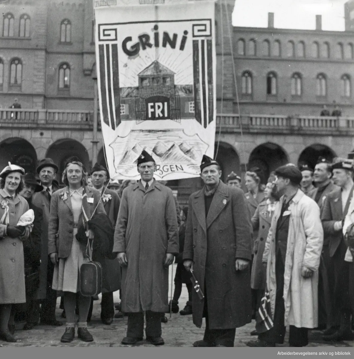I midten fhv. stortingsmann Karl M. Johannessen. Ved hans venstre side står Gerd Svendsen og til høyre, .ordfører i Laksevåg Alf Pettersen. Løslatelsen av fanger på Grini. Bergensere foran sin Grini-fane på Youngstorget, mai 1945.