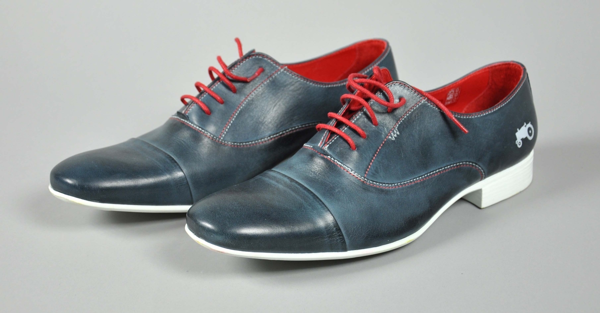 Et par blå skinn herresko i str.44,røde skolisser,røde og hvite sømmer .
Traktor-logoen påtrykt i hvitt på begge skoene.