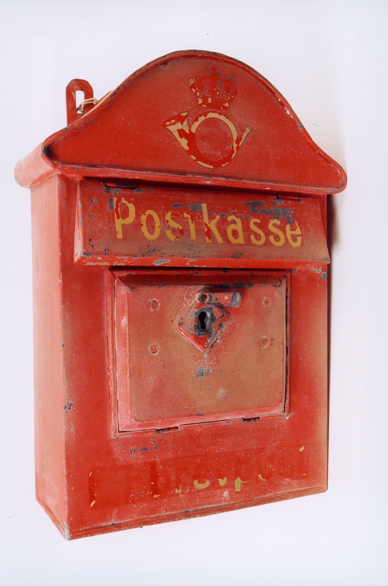 Rød tømmepostkasse. Låsbar. Posthorn og ordet Postkasse og ordet brevpost.  Malingsslitt.