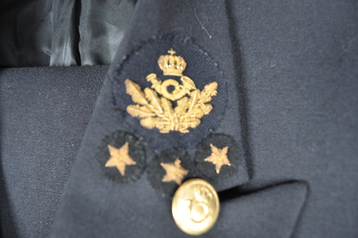 Uniformen er mørke blå og består av jakke og bukse. Gullknapper og postlogo med eikeløv og tre stjerner.