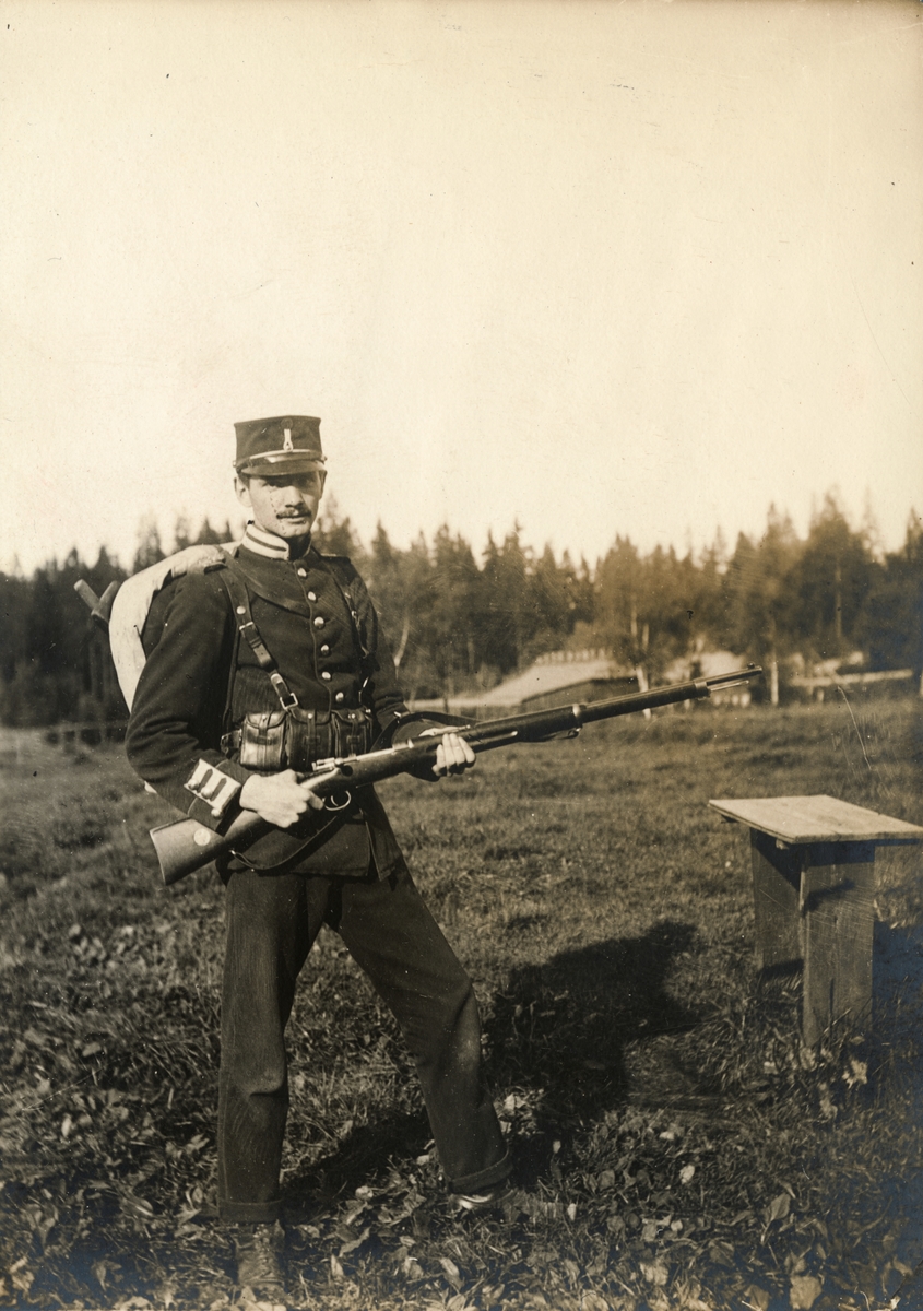 Soldat vid Göta livgarde I 2 med ränsel på ryggen och gevär i händerna.