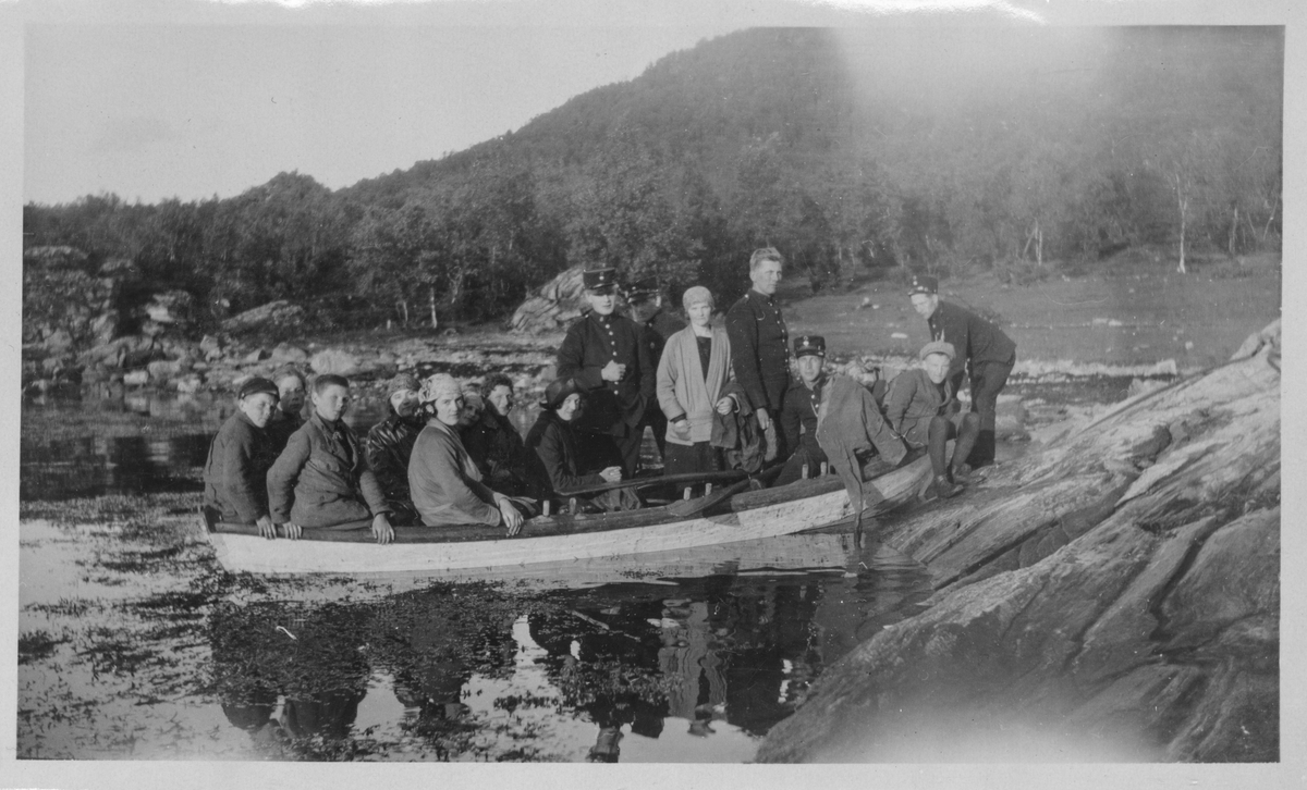 Kvinner, barn og soldater på utflukt i en robåt.