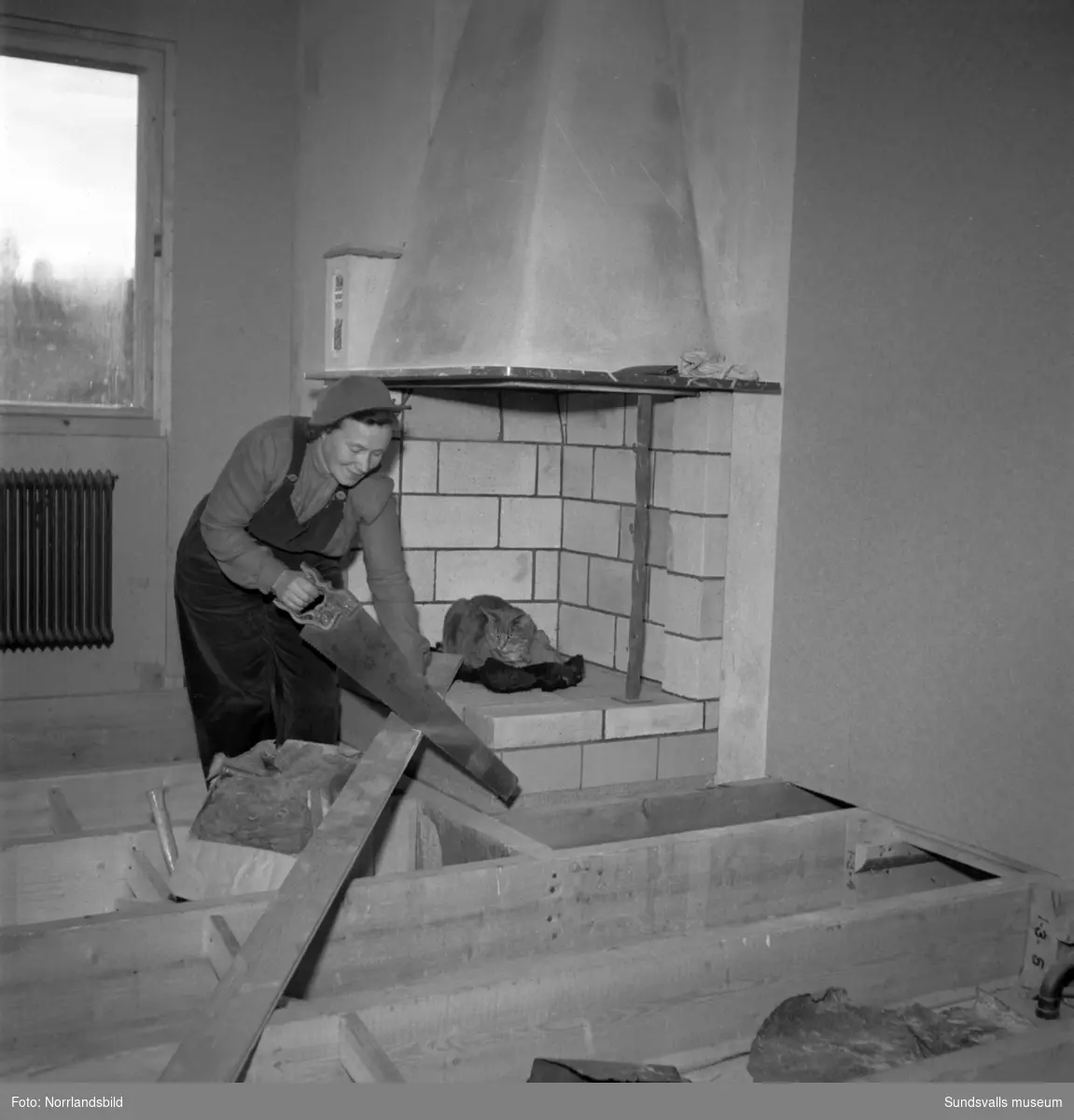 Husbyggande fru i Nacksta. En kvinna och en katt vid ett villabygge på Sallyhillsvägen 69.