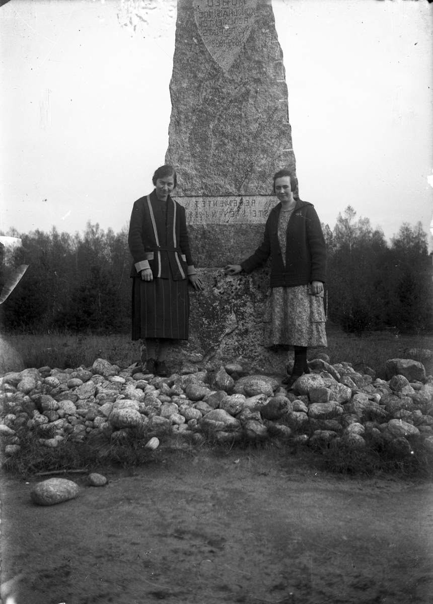 Två kvinnor vid Mohed regementes monument (sten).