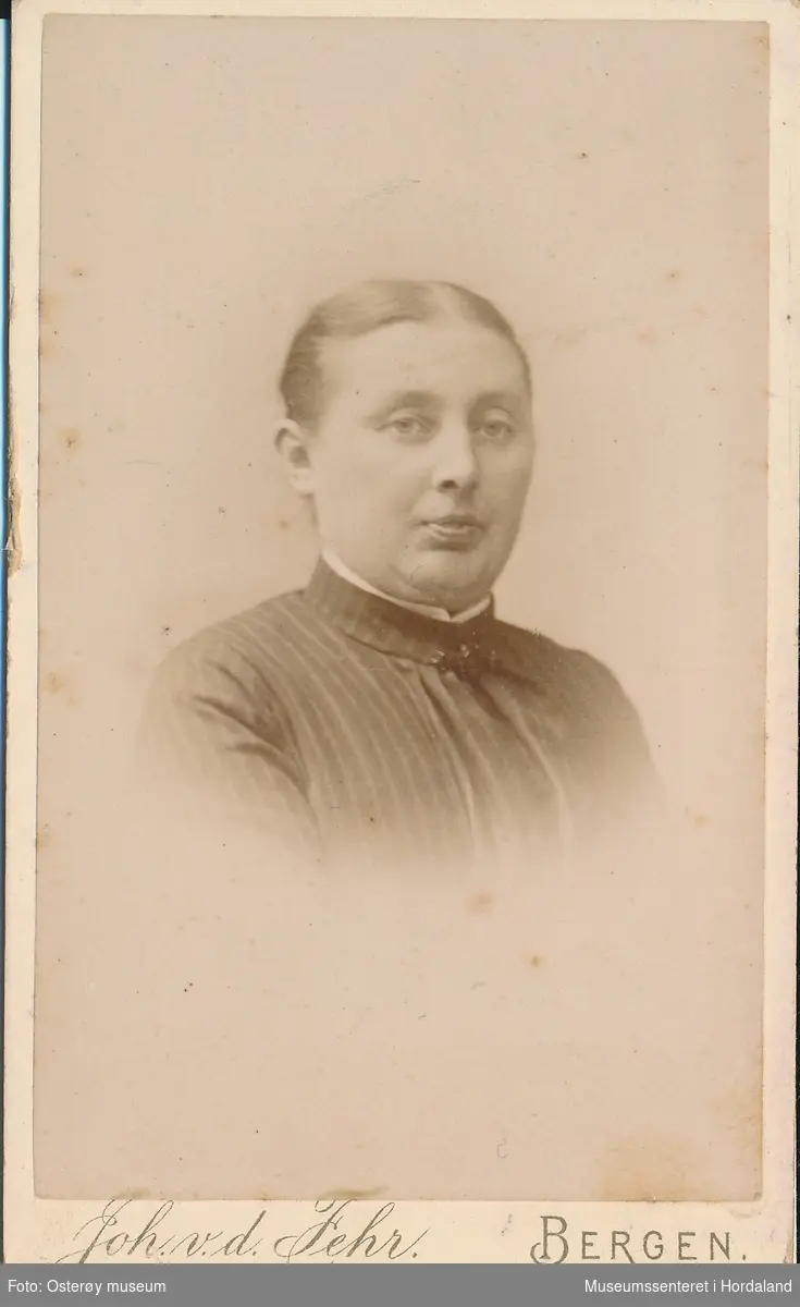 portrettfotografi av kvinne med midtskill, stripa mørk bluse/jakke med kvit krage inni