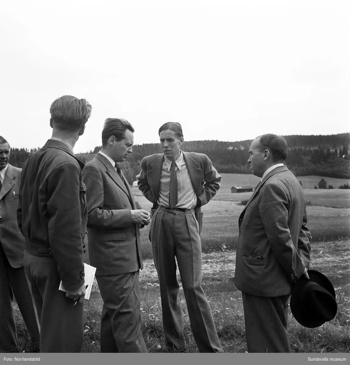 En grupp män står vid gravfältet i Högom. Näst längst till höger på första bilden Sverker Jansson som ledde utgrävningarna tillsammans med Dagmar Selling.