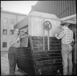 To menn arbeider på en maskin utenfor Norullfabrikken i Havn