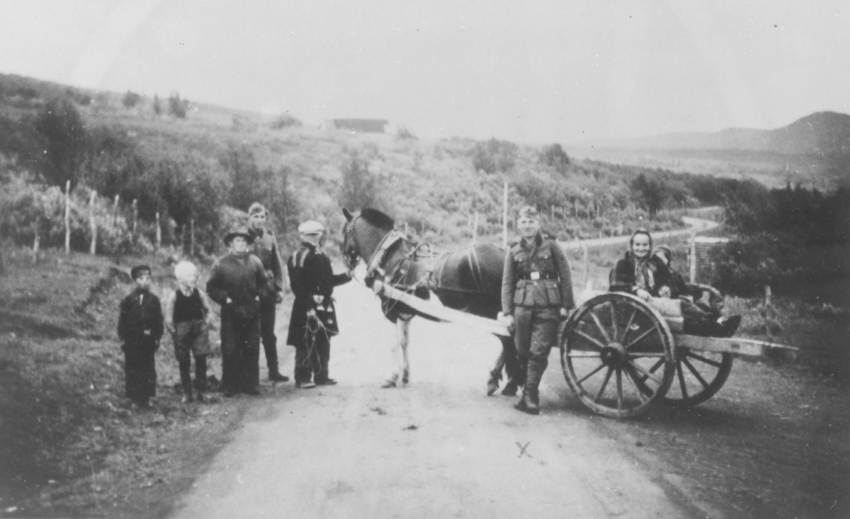 På veien i Nesseby under krigen. Kvinnen som sitter på vogna og mannen som holder hesten er Birgit Koi (fra Nesseby) sine svigerforeldre. Soldaten foran er østeriker.