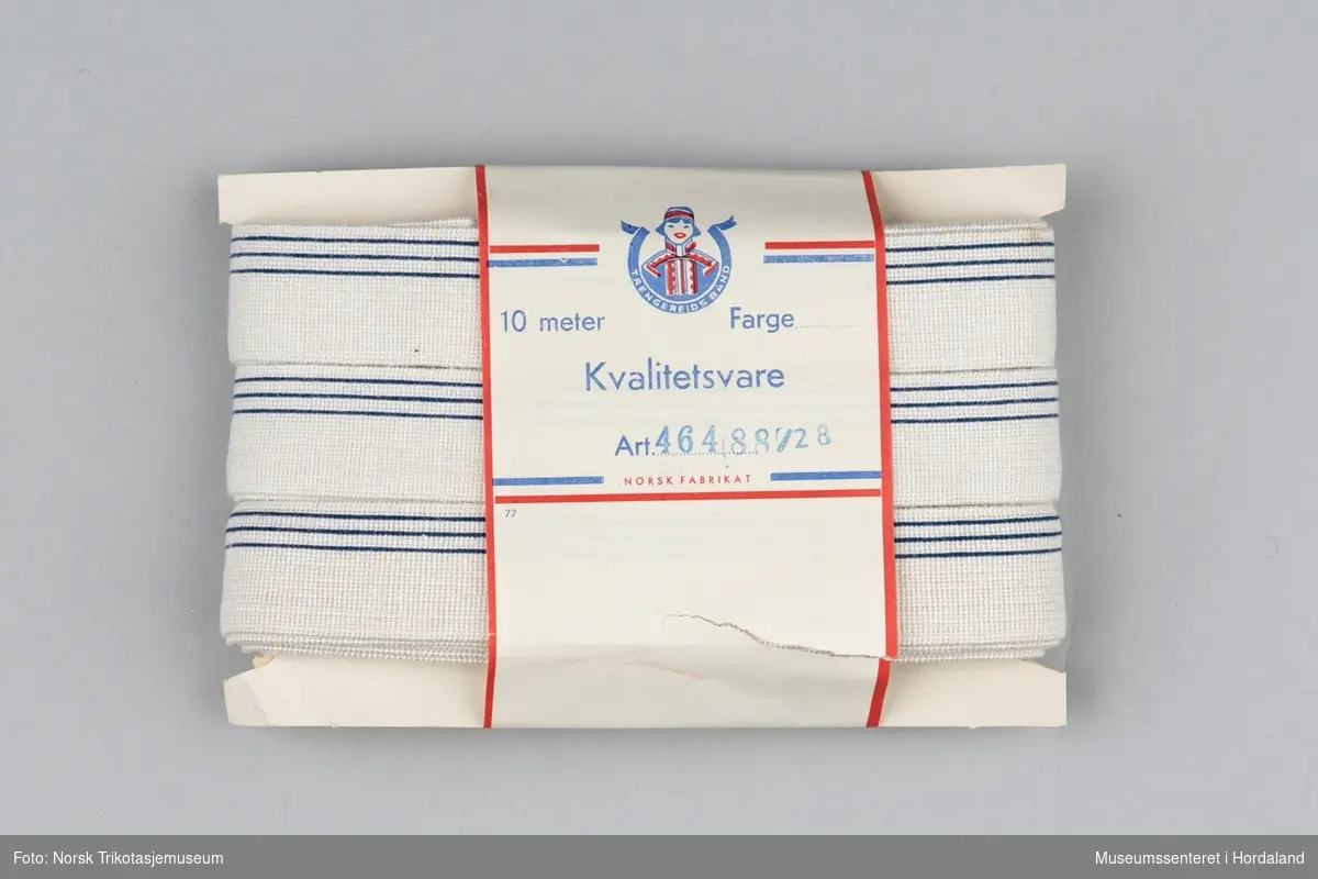 Kvit strikk/elastikk med mørkeblå striper, med papp/papiremballasje. Produsert ved Trengereid Fabrikker.