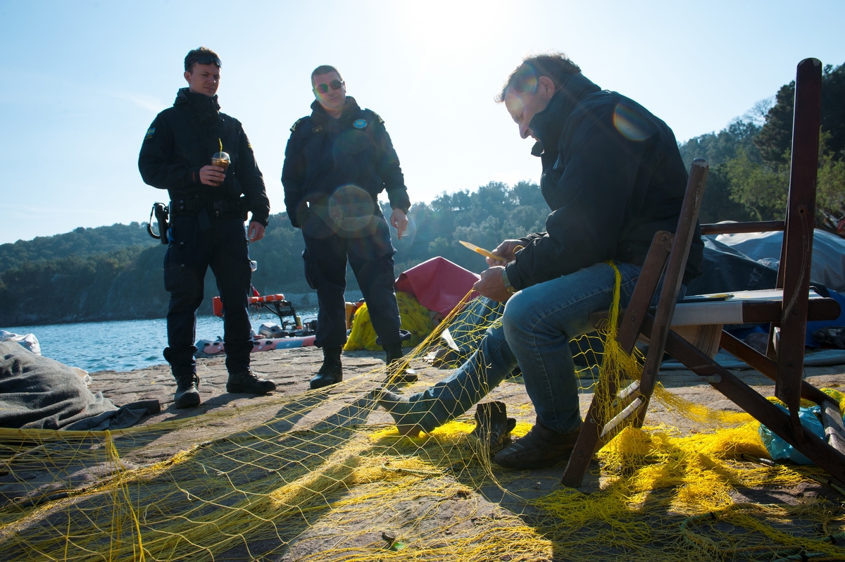 Besättningsmedlemmar dricker kaffe och pratar med fiskare i hamnen i Skala Sikamineas.