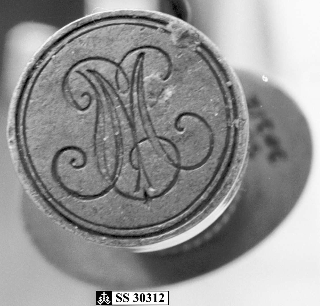 Stempel av messing med initialer på toppen av håndtaket.