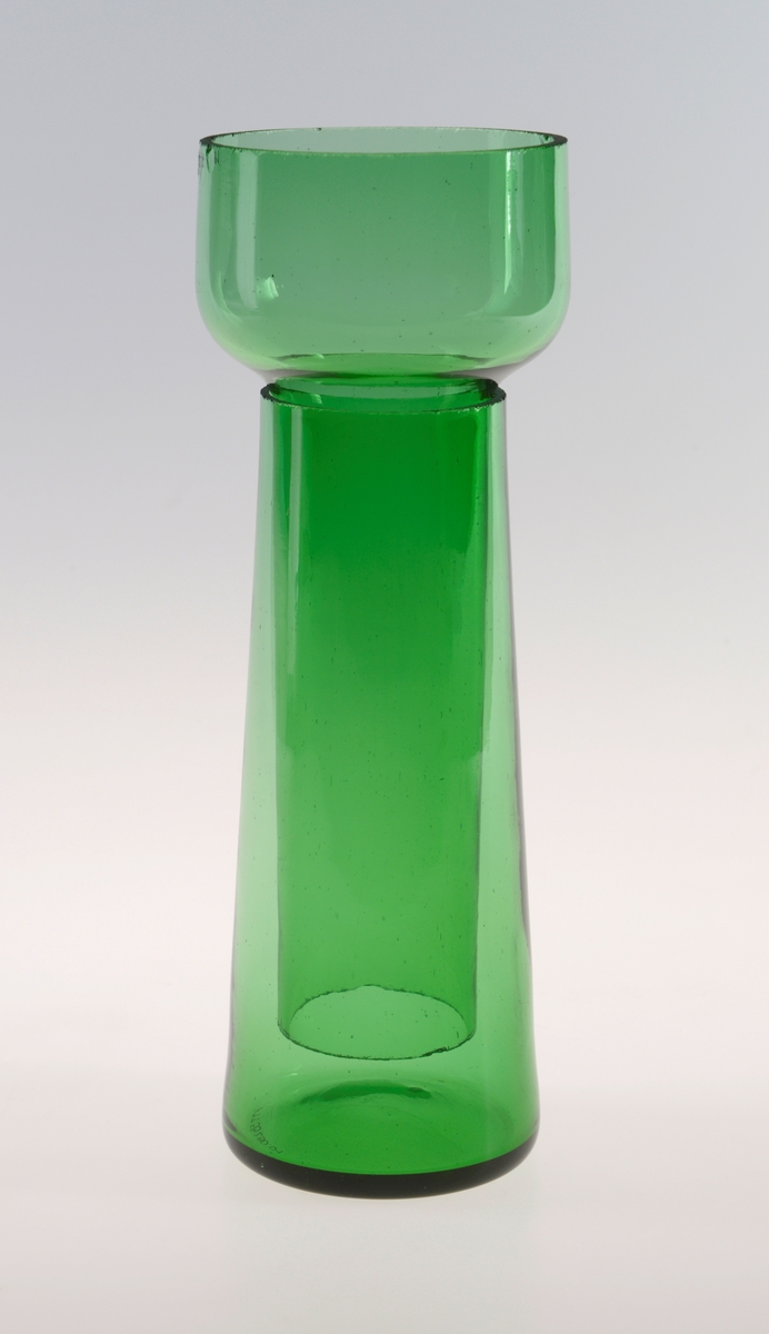 Todelt svibelglass i grønt håndblåst glass hvor svibeldel går oppi vasedel. Vasedelen er konisk formet, og svibeldelen av glasset er sylinderformet. Svibeldelen er i tillegg bredest øverst, som gir plass til svibelløken.