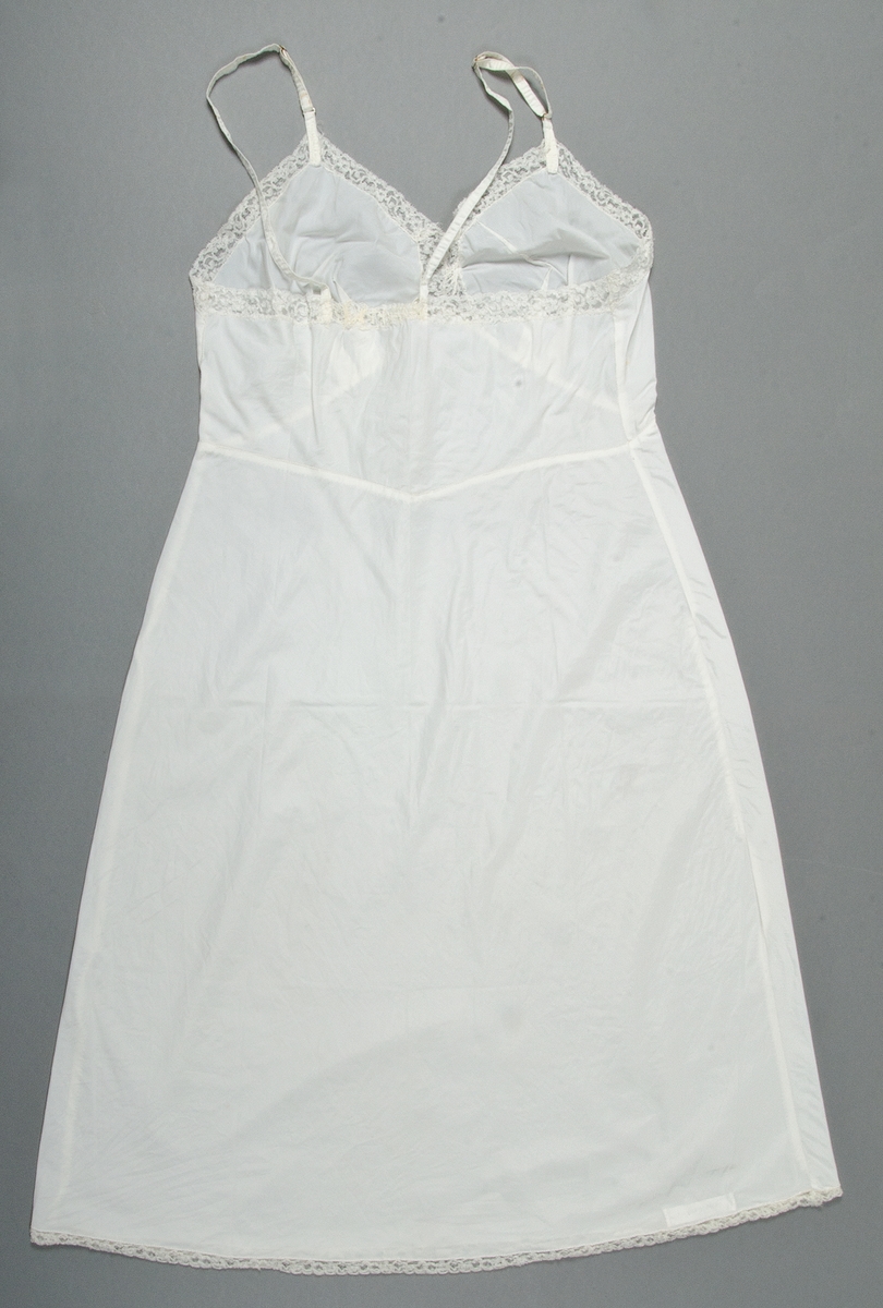 Underklänning av vitt tuskaftat konstsiden. Kantad med vit nylonspets.