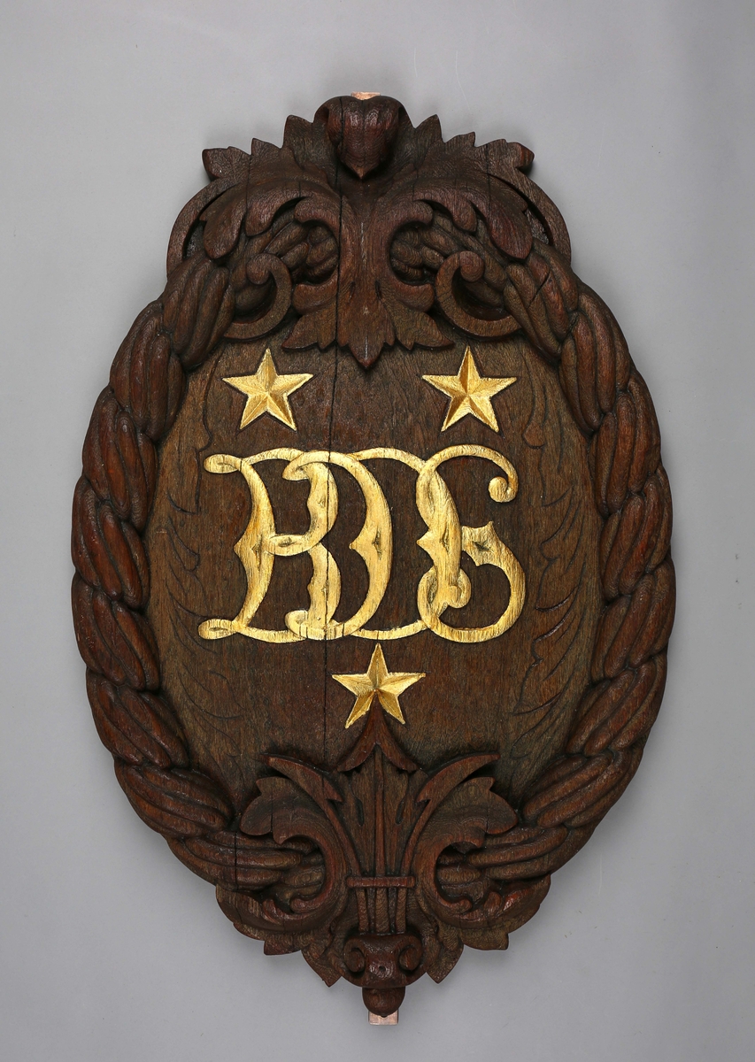 Emblem dekort med tau og bokstavene BDS utskårtet i tre.