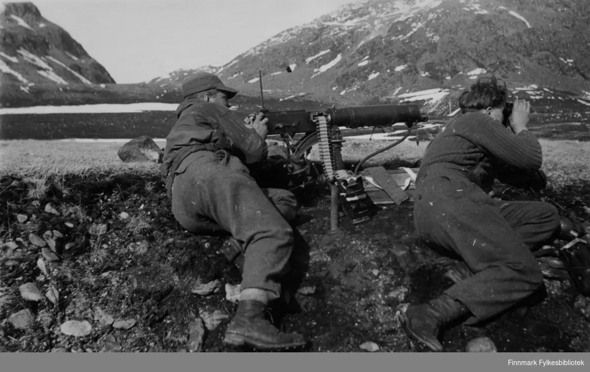 Hopseidet 1945, april-mai. To soldater tilhørende Distriktskommando Finnmark i stilling med vannkjølt Colt-mitraljøse M1929. Trolig andre tropp i 2. Bergkompani. Dette bildet finnes også i Rune Rautios samling, i et fotoalbum med et større antall bilder. Fotoarkivet har fått kopi av dette albumet og fått tillatelse til å gjengi bildetekstene. 

Det kom 2 stk. Colt mitraljøser til Hopseidet 8 mai 1945. Ved Bergkompaniet ble 2. tropp under Løytnant Håkon Nordhaug med 2 mitraljøser og 2 bårelagsfolk gjort klar til unnsetning og besettelse av Hopseidet og 7. mai ble de sendt med m/k "Havørn". 8. mai kunne Løytnant Nordhaug sende denne meldingen til DK sjefen: "Ankom Hopseidet 05:59 med 42 mann".

[Harald Sandvik, "Frigjøringen av Finnmark 1944-45", s169]


Bildeserien "Frigjøringen av Finnmark 1944-45" viser et unikt materiale fotografert av soldater i Den Norske Brigade, 2. Bergkompani under deres oppdrag "Frigjøringen av Finnmark" som kom i stand under dekknavn "Øvelse Crofter". Fakta rundt dette bildematerialet illustrerer iflg. vår informant, George Bratli: "2.Bergkompani, tilhørende Den Norske Brigade i Skottland,  reiste fra Skottland 30. oktober 1944 med krysseren «Berwick» til Scapa Flow på Orkenøyene for å slutte seg til en større konvoi som skulle være med til Norge. Om bord på andre skip var det mange russiske krigsfanger som hadde vært på tysk side og som nå ble sendt hjem. 
2.Bergkompani forlot havn 1.november 1944 og kom til Murmansk, Sovjetunionen, 6. november 1944. 
De ble her lastet om og fraktet til Petsamo, Sovjetunionen, hvor de ankommer 11.november 1944. 
Kompaniet reiser så til Sandnes utenfor Kirkenes og blir forlagt der frem til 26.november 1944. De flytter så videre til Skipparggura. 
Den 29.november reiser deler an kompaniet til Rustefielbma og Smalfjord og noen drar opp på Ifjordfjellet. 

17. desember ankommer resten av kompaniet til Smalfjord. 30.desember blir en avdeling sendt til Hopseide og 8. januar 1945 blir noen sendt til Kunes.
Den 14. januar er kompaniet delt og ligger i Kunes, Kjæs, Børselv, Hopseide og Smalfjord.
5. februar 1945 blir 3.tropp sendt over Porsangerfjorden for å operere i Olderfjorden. Her var de i kamp og hadde tap i  Billefjord og Sortvik.
8.mars 1945 kom noen til Renøy og 12. mars kom første del av kompaniet til Brennelv.
7.mai begynte kompaniet å bygge ny kai i Hambukt.
19. mai ble de som hadde falt begravd i Lakselv.
8. juni ble kompaniet flyttet fra Brennelv til Tromsø for så å bli sendt videre til Mo I Rana 16.juni."

Nasjonalbiblioteket har et hefte fra 1983 skrevet av Krigsinvalideforbundet, med intervjuer med soldater og deres opplevelser: 
https://www.nb.no/items/5d58d366b390666f671f57078519c2c7?page=0&searchText=Det%20glemte%20kompani%20-%202.%20Bergkompani%20og%20frigj%C3%B8ringen%20av%20Finnmark

Arkivverket har også bilder og tekster om hendelsene:

https://www.arkivverket.no/utforsk-arkivene/andre-verdenskrig/befolkede-jordhuler-kjokken-i-det-fri-og-midlertidige-begravelser-privat-bildesamling-etter-soldat-i-2.bergkompani
