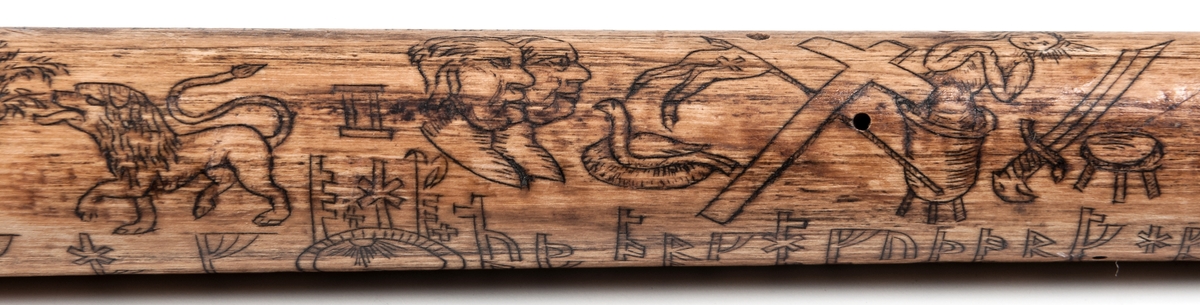 Käpp av trä med runkalender och krycka i form av ett utskuret manshuvud. Runor och figurer efter almanack eller annan tryckt kalender. Märkt "SC 1784" och "MC 1793".