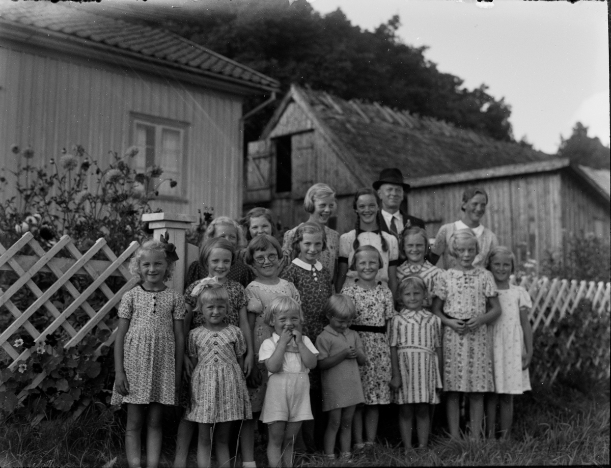 Sexton flickor (möjligen en pojke) på Kerstin Johanssons 10-årskalas den 18 augusti 1939 i Albäck. De står på utsidan av trädgårdens vitmålade trästaket, varöver dahlior, rosor och andra sensommarblomster skjuter upp. Slipens Klas står baktill i hatt och kostym.
Bland barnen syns bland annat Margit Larsson, Gerda Johansson på Nytorp, Lundgrens Ella (fosterbarn hos Anders Lundgren), Inga i Kantabur, Anna Greta i Kantabur, Karin på Nytorp (Larsa Karin) och "Banvaktarens" lilla Sonja Andersson.