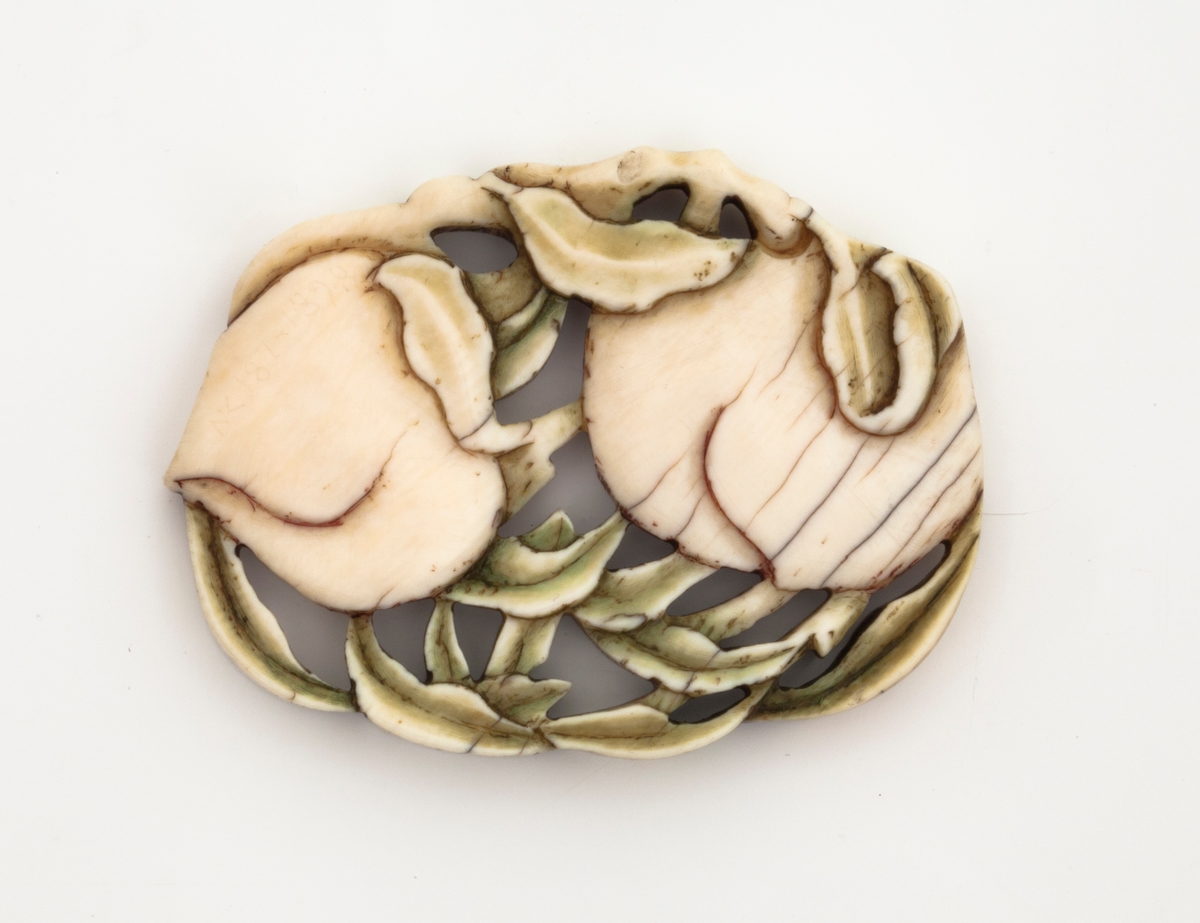 En oval elfenbensplate med utskjæringer av 2 ferskener med blader.