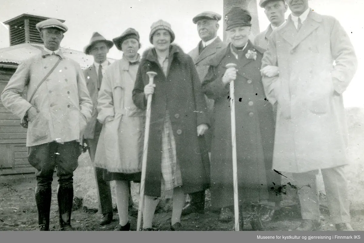 Gruppe besøkende ved Oscarstøtten på Nordkapp-platået. Krigskommisæren t.v. I bakgrunnen posthuset. 1930-tallet.