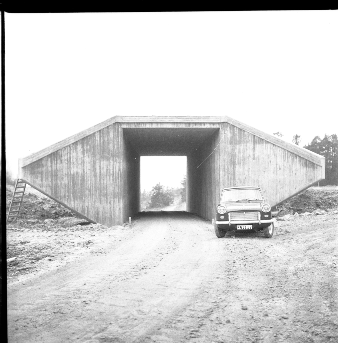 En viadukt (så kallad ko-port för att köra kor till marker på andra sidan motorvägen) i samarbete med motorvägsbygget vid Gränna, etapp II. En personbil parkerad hitom viadukten.
