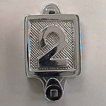 Fyrkantig vändbar skylt som kan låsas med fyrkantnyckel. Skylten är av förnicklad, silverfärgad mässing med siffror i relief mot räfflad botten.
På ena sidan står det:
"1".

På andra sidan står det:
"2".
