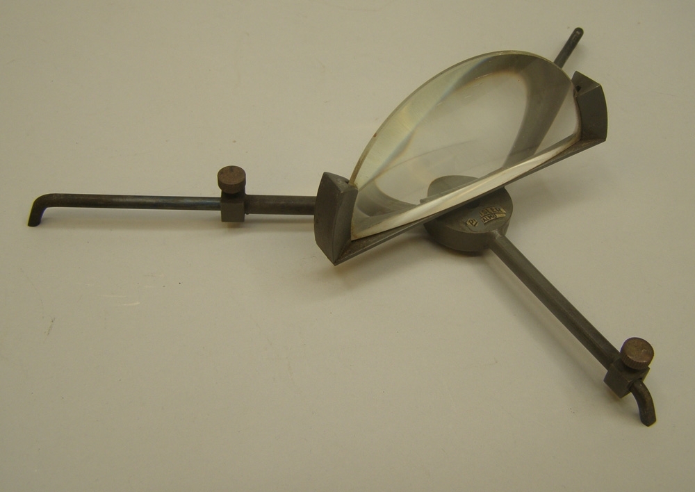 Instrument av mässing målad i mörk brunblå kulör som tillhört ångfärjan Starke. Mitt på instrumentet är ett förstoringsglas fastsatt med ett gångjärn av mässing.