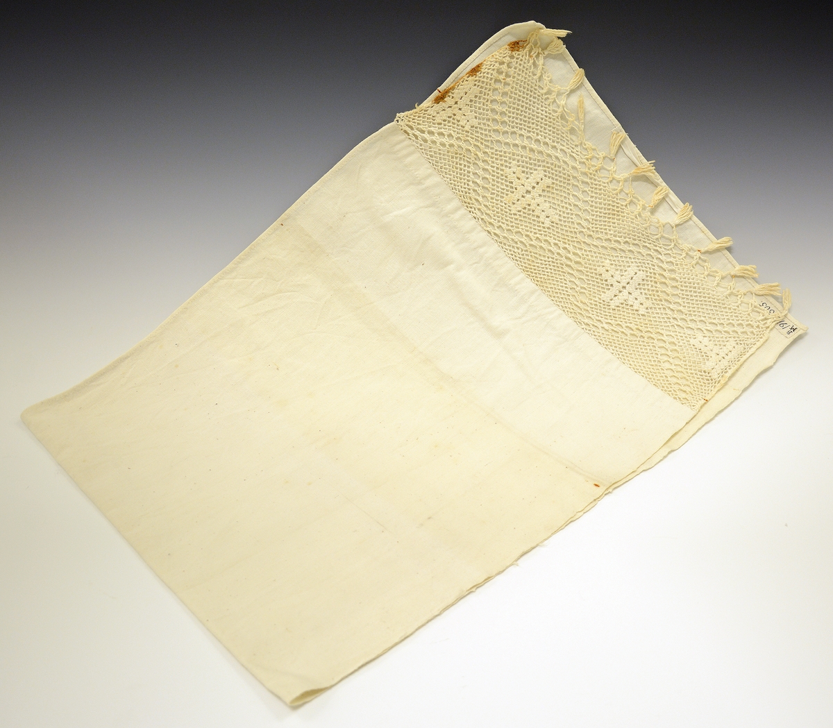 Fra protokollen: Haandklæde (d.v.s. hangklæde) med bred flette forneden. Håndvevet bomull.