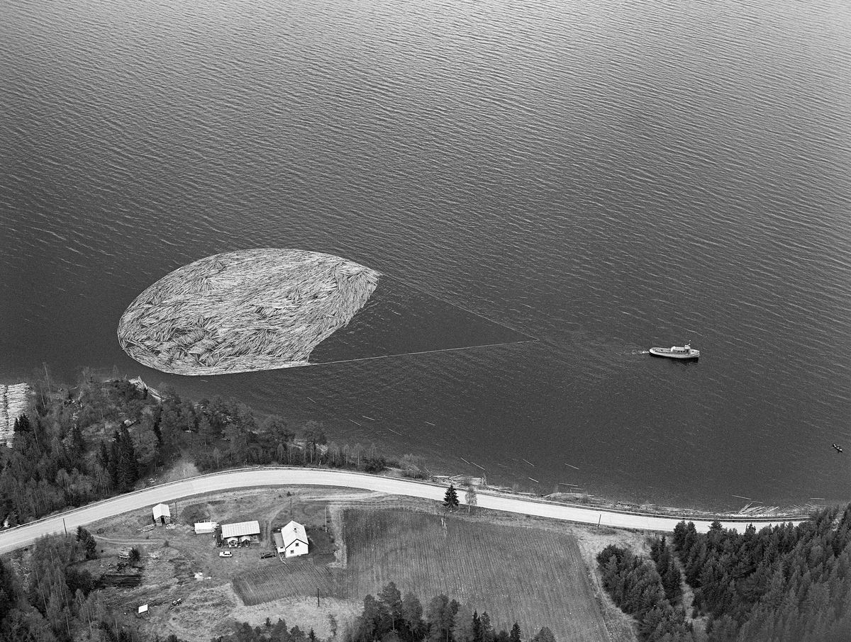 Flyfotografi, tatt over Fiskvikstøa i Ytre Rendalen, på Storsjøens vestside i 1981.  Vi ser hvordan riksveg 30 (her også kalt «Gamle kongeveg») slynget seg langs strandlinja. Mellom vegen og strandlinja, nederst til venstre i bildet, lå det en utislagsplass for tømmer som ble transportert til hovedvassdraget på lastebiler.  På vannspeilet ser vi en ringbom som ble slept sørover av tømmerslepebåten «Storsjø».  Det tok vanligvis drøyt 30 timer å trekke en slik ringbom fra området ved Åsheim i nordenden av innsjøen til utløpet i elva Søndre Rena, om lag 36 kilometer lengre sør.  Med de store tømmermengdene som ble fløtet i 1950- og 60-åra ble det gjerne omkring 30 turer, og sesongen varte om lag to måneder.  Da dette fotografiet ble tatt, i 1981, kunne 10-12 ringbommer romme de cirka 17 000 kubikkmeterne med slipvirke som skulle fløtes ut av Rendalen.  Virksomheten ble avviklet etter 1984-sesongen.