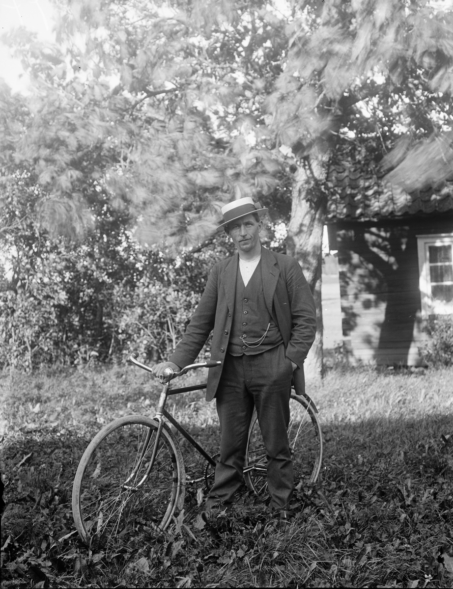 Man med cykel i trädgård, Sävasta, Altuna socken, Uppland