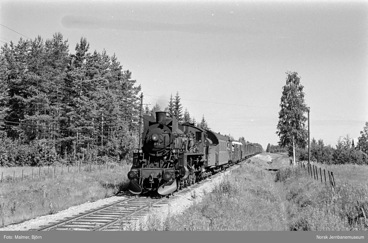 Godstog fra Elverum til Kongsvinger i nærheten av Grinder stasjon. Toget trekkes av damplokomotiv type 26c nr. 433. Bak lokomotivet personvogn litra BF3 nr. 19903.