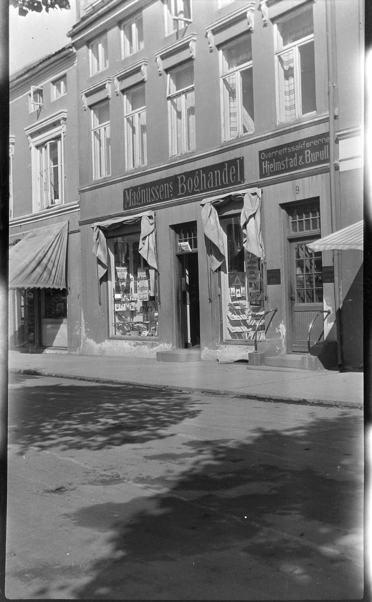 Strandgata Hamar. Butikk fasade, Magnussens Bokhandel, utstillingsvindu,  Overrettsaksførerne Hjelmstad&Burull.