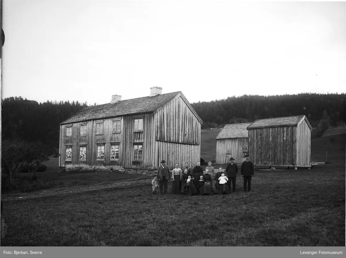 Familie foran et gårdsbruk, uidentifisert sted.